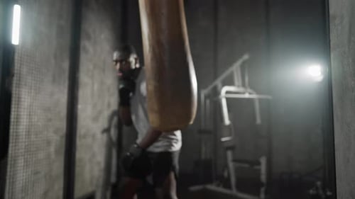 Boxer Training Hitting Punching Bag African American Sweated Sportsman Practicing Punches in Gym