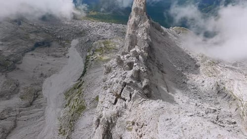 Breathtaking drone shot of rocky mountains with flying clouds and green valley in Dolomites - tilt u