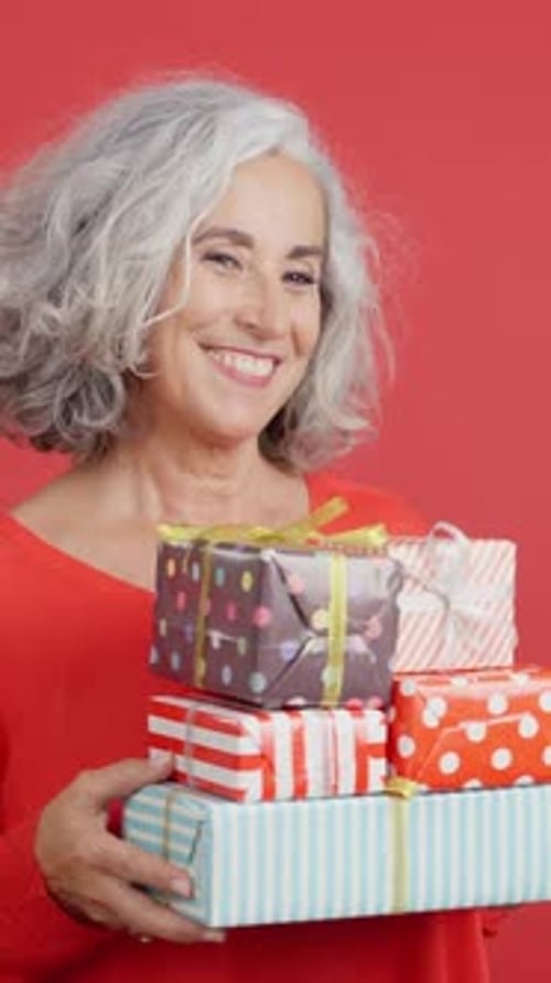 Smiling Senior Woman Holding Wrapped Christmas Gifts