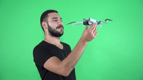 Young man spreading drone wings and preparing for flight on green screen 4K