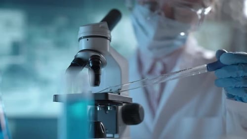 Laboratório de Ciências Médicas Um microbiologista usando óculos está examinando o microscópio