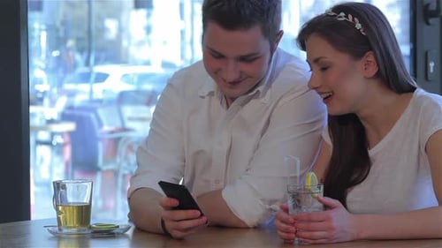 Couple Looking at Smartphone in Cafe