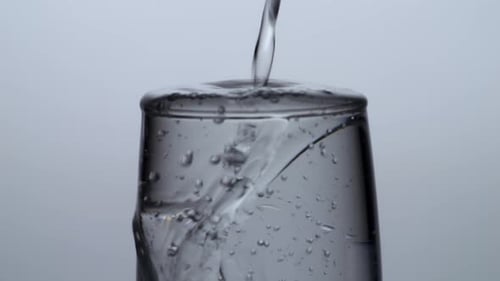 Close Up Of Drinking Water Being Poured Into A Glass On The Light White Screen Background