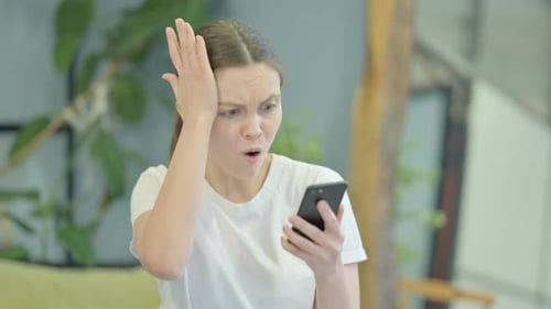 Woman Reads Bad News on Smartphone, Reacts with Shock
