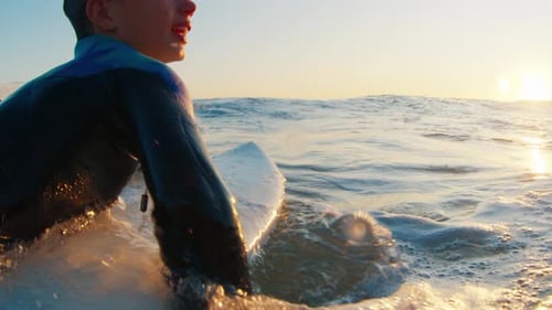 Surfer Paddling Out at Sunset