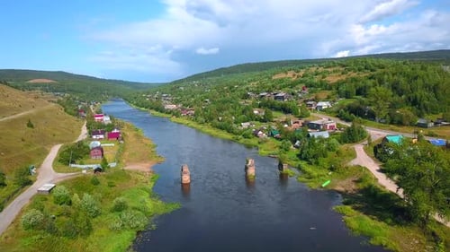 Top view of ruins of old bridge on river with village