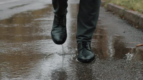 Front View of Male Feet in Shoes Dancing on the Wet Asphalt in the Autumn City Park in Rain Close Up