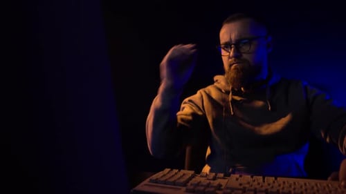 Man Working at Computer in Dimly Lit Room