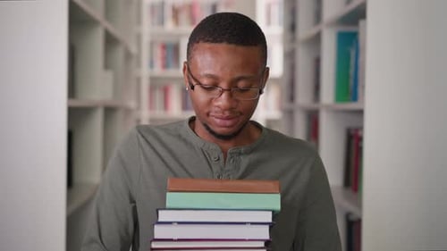 Black Teacher with Book Stack in Library