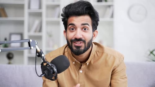Webcam view. Confident young man recording podcast using microphone while sitting in home office