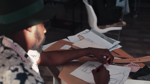 Man Designing Clothing Patterns in Studio Workspace