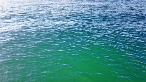 Luftaufnahme von oben auf ein transparentes blaues Meer mit schönen Wellen an sonnigen Tagen im Sommer. Meeresluft