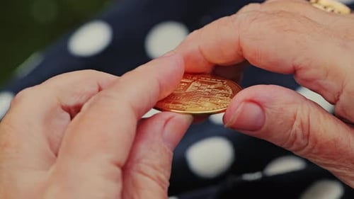 Elderly woman holding bitcoin coin in hands, slow motion close up