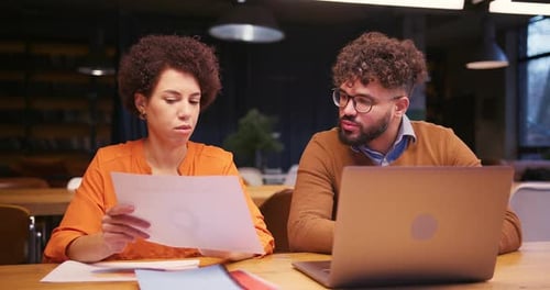 Businesswoman and Businessman Working Together in Modern Office Analyzing Documents Using Laptop