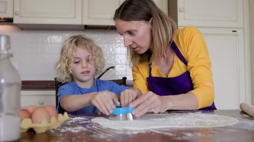 Familienkochen: Kind, Sohn und Mutter bereiten Kekse in der heimischen Küche zu