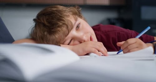 Tired Student Resting Fatigued White Teenager Relaxes At His Desk Amid Homework And Soft Lighting
