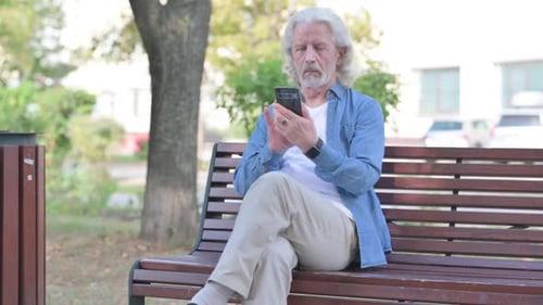 Senior Man Using Smartphone on Park Bench