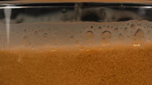 Beer is poured into a glass close up. Beer foam in a glass with bubbles from fermentation