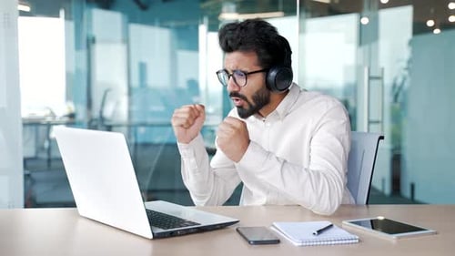 Man Celebrating Success at Laptop in Modern Office