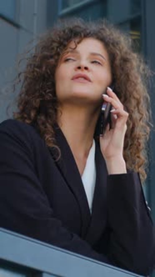 Mujer de negocios tranquila caucásica hablando por teléfono móvil relajándose en el balcón de la oficina Empresaria