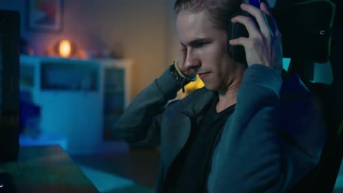 Young Man Puts on Headphones to Play Video Games