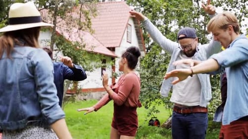 Happy hispanic friends dancing together at groovy summer garden party