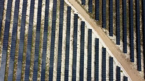Solar panels farm aerial view from drone shot while sun setting. Small photovoltaic cell panels fiel