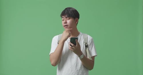 Asian Man Student Using Mobile Phone And Thinking Then Raising His Index Finger On Green Screen