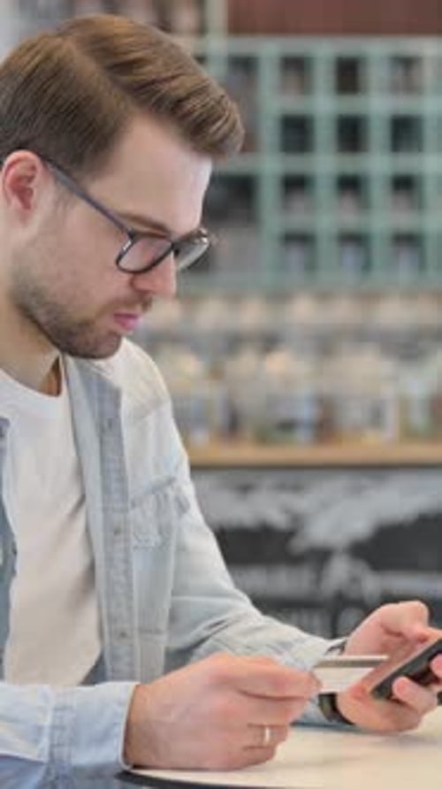 Young Man Uses Credit Card with Mobile Phone