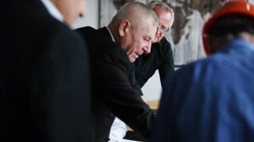 Aged team of elderly businessman architects have a meeting in the office and talking