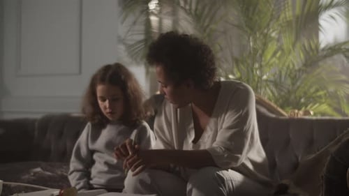 Woman and Child Studying Together on Sofa