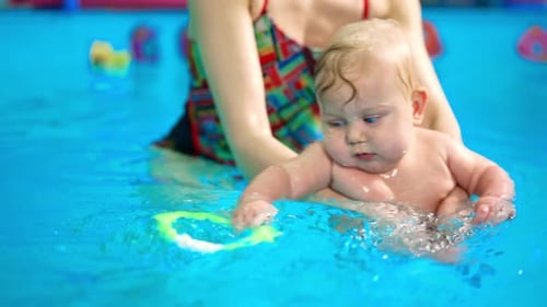 Baby Swimming with Assistance in Bright Blue Pool