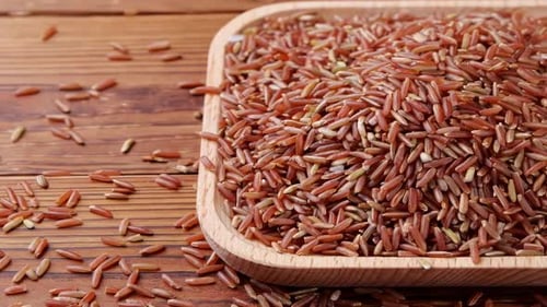 Brown Rice in Wooden Bowl on Wood Surface