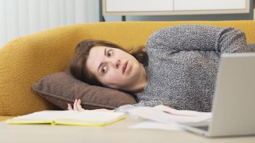 Woman Relaxing on Couch with Laptop and Notebook