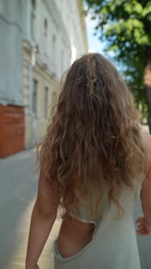 Walking Through the Sundappled Evening City a Girl's Red Curly Hair Adds to Her Allure