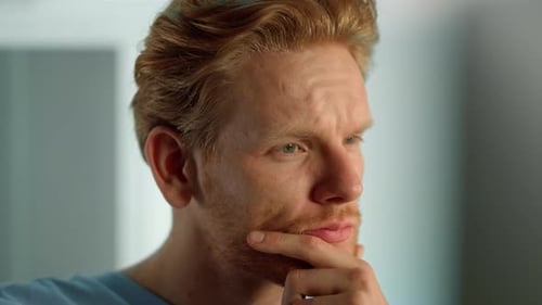 Contemplative man with red hair thinking deeply indoors
