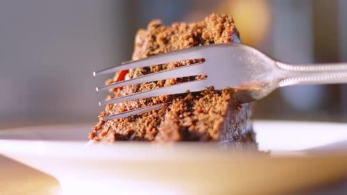 Close Up Fork Cutting Bite Sized Piece of Indulgent Cake to Eat.