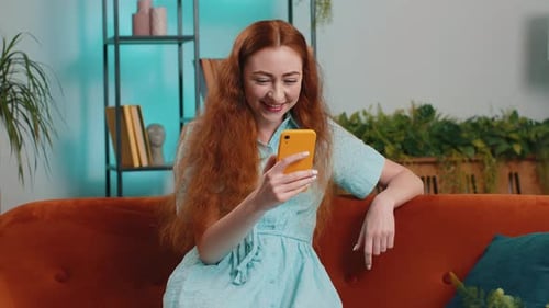 Woman Sitting on Couch Looking at Cell Phone