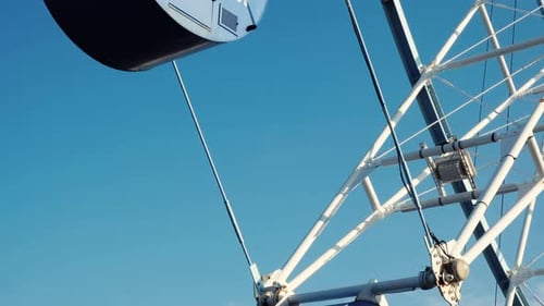 Ferris Wheel Cabin Ascends Against Blue Sky