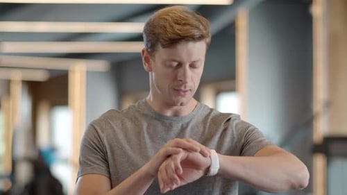 Portrait of Attractive Sportsman Checking Results in Fitness Center. Tired Fitness Man