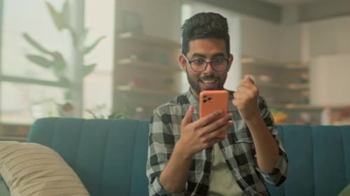 Man Sitting on Sofa Using a Mobile Phone