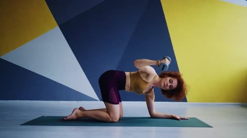 Woman Working Out with Dumbbell on Yoga Mat