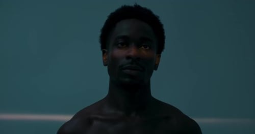 Young Serious Man Standing in Studio Isolated Blinking Looking Directly at Camer Close Up Shot Dark