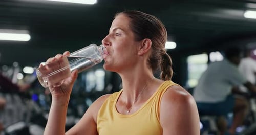 Happy woman, drinking water and fitness with hydration in gym for rest, recovery or workout break