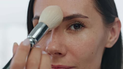 Woman Applying Makeup With Brush in Close Up
