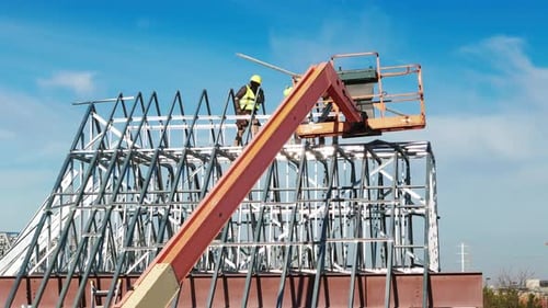 Industrielle Dachdecker, die ein Dach auf einem Industriegebäude oder einer Lagerhalle installieren, Drohnenaufnahmen