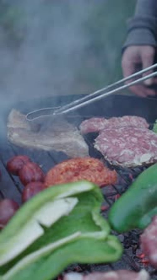 Nahaufnahme eines Mannes, der Kochklemmen benutzt, um das Fleisch in Zeitlupe umzudrehen