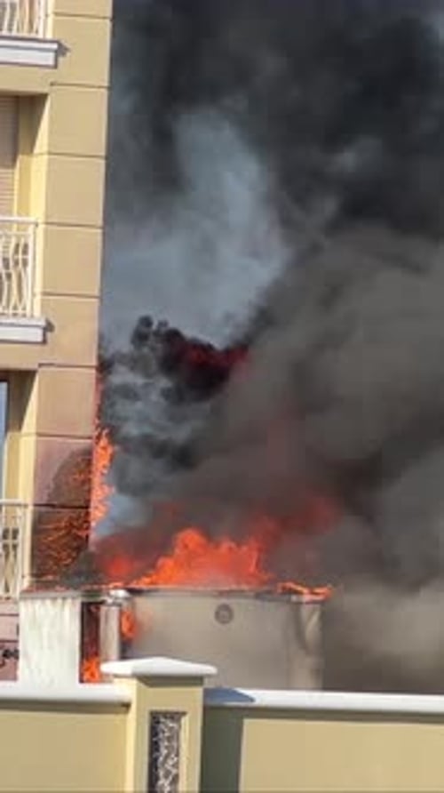 Beach apartment condo building on fire, flames and black smoke, daytime