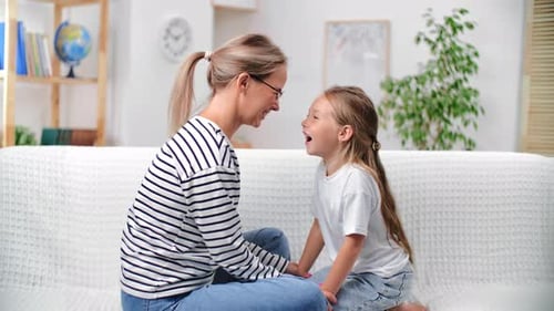 Woman and Child Chatting on White Couch Indoors