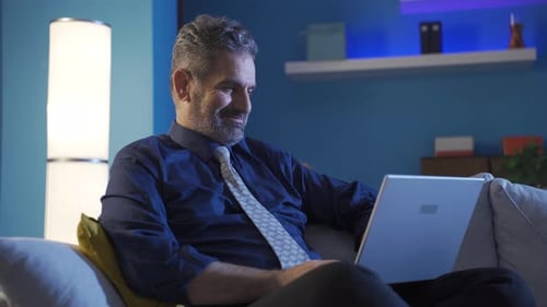 Mature Man Relaxing on Sofa Typing on Laptop